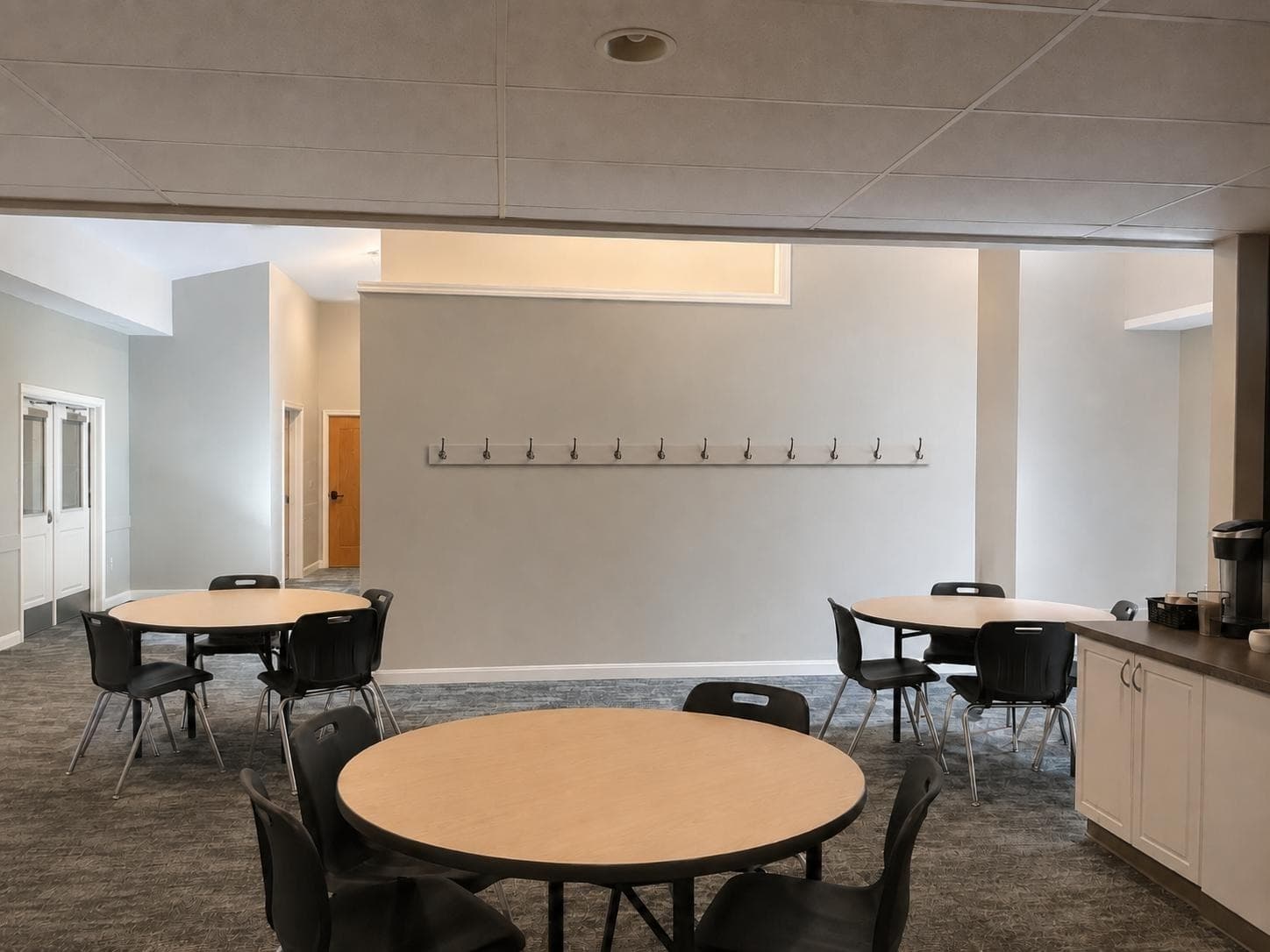AI-generated image of the finished commons with round tables and coat hooks