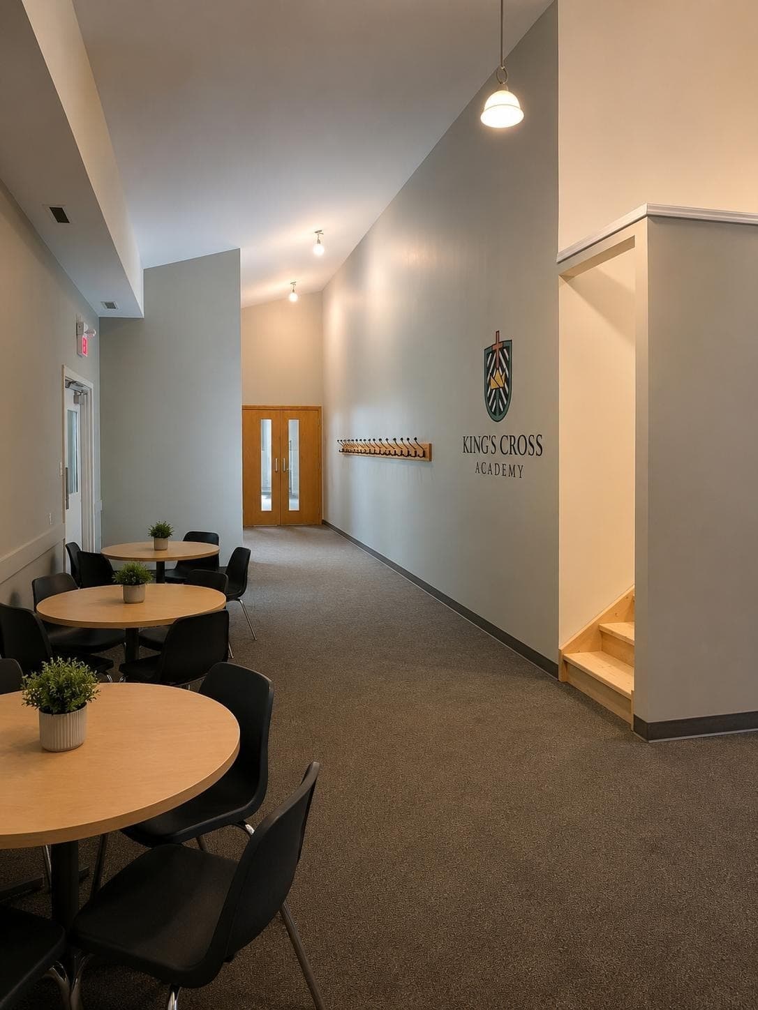 AI-generated image of the finished hallway with tables, coat hooks and the school crest