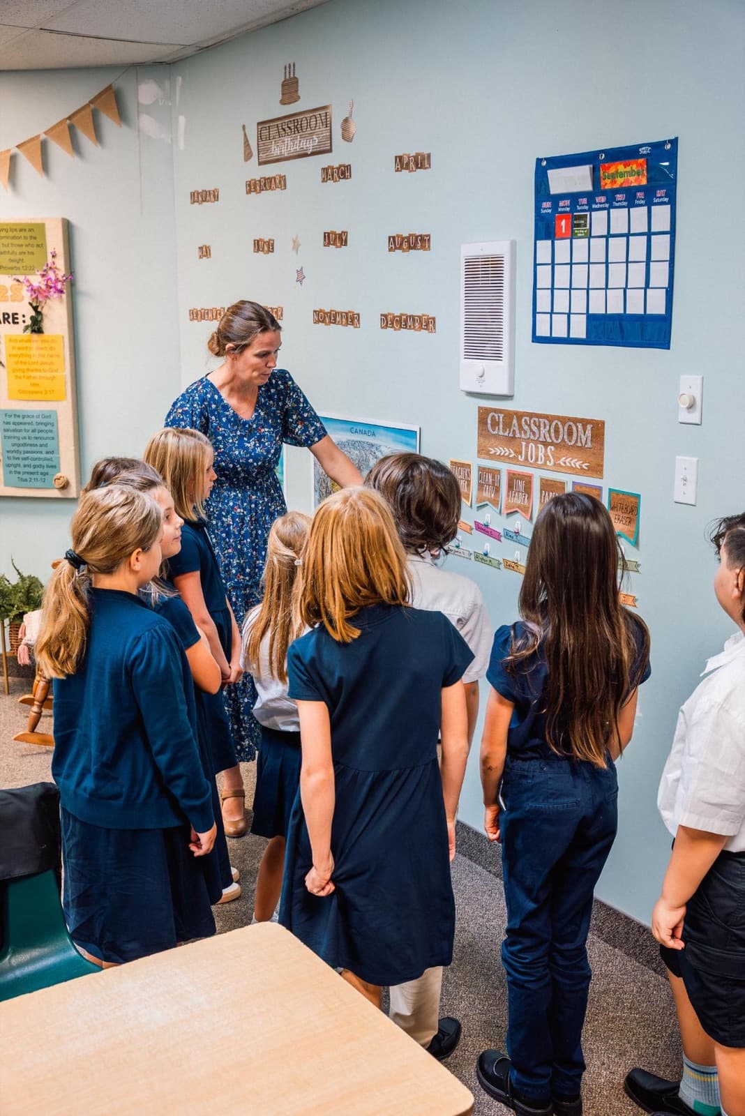 Students gathered with their teacher at the classroom jobs wall